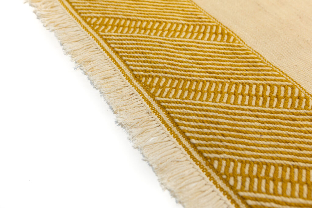remate de kilim geometrico de color mostaza y beige.